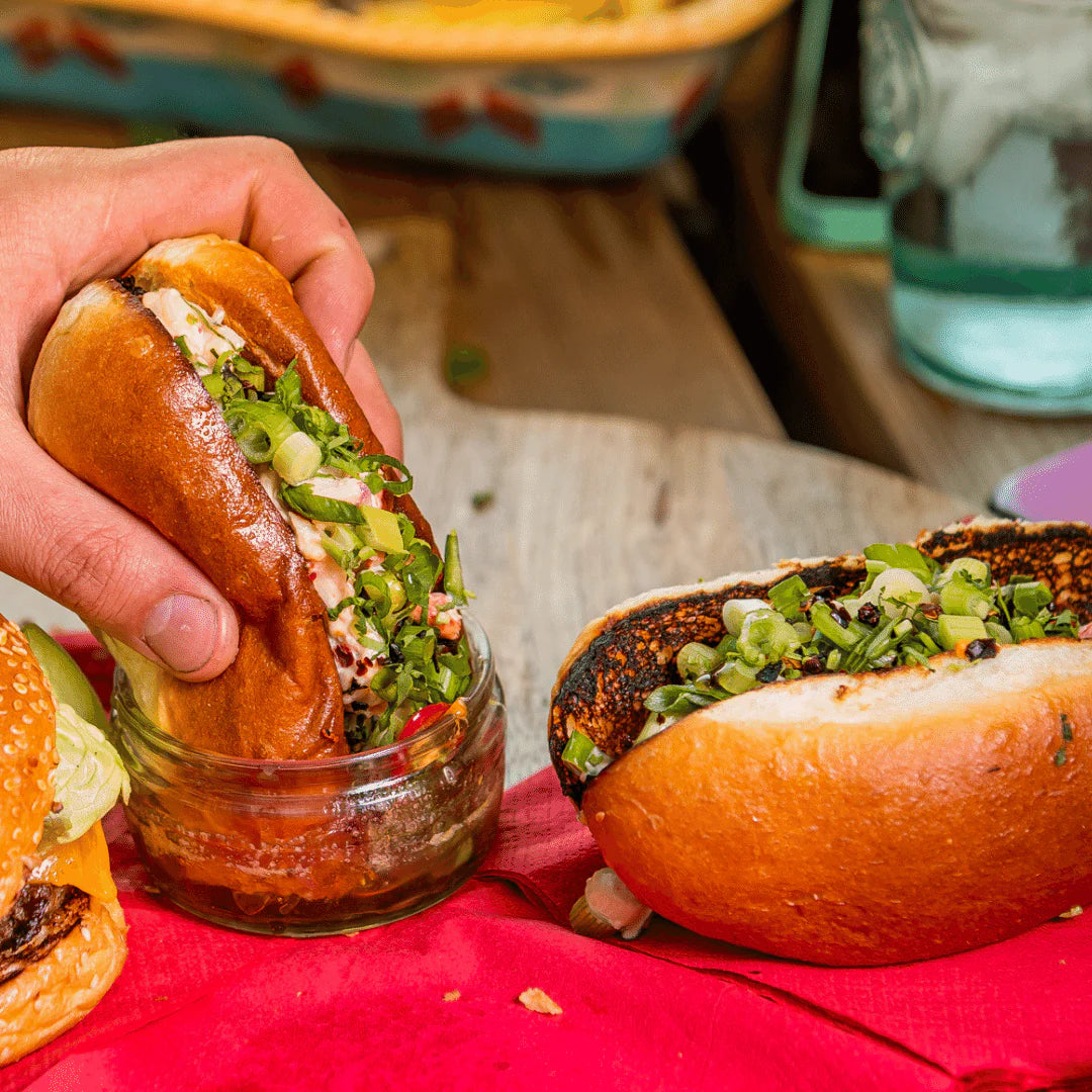 Gourmet Lobster Roll Kit with fresh lobster and green onions in a soft bun held by a hand