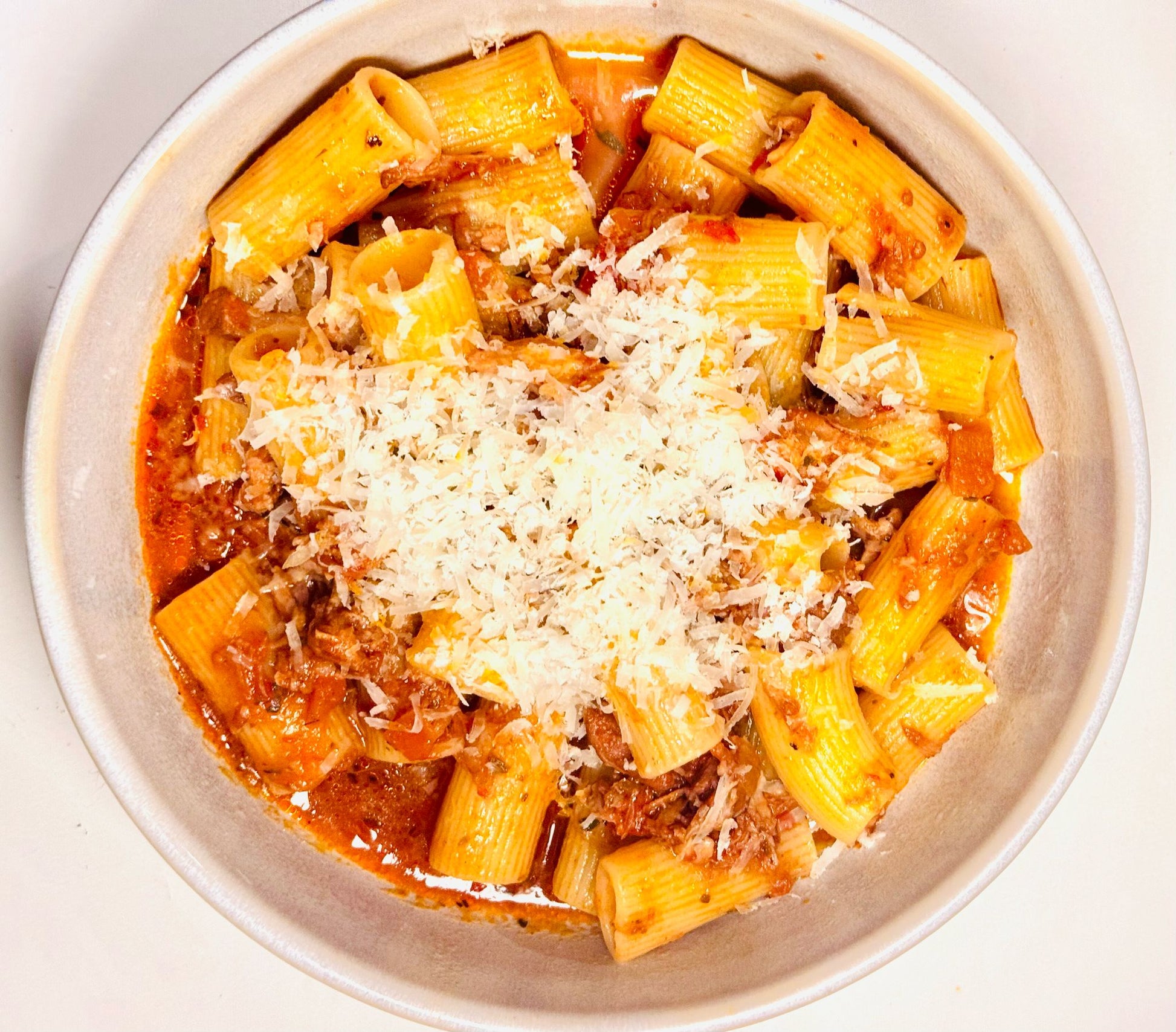 Delicious Flayvr pasta kit featuring cooked rigatoni topped with rich meat sauce and grated cheese