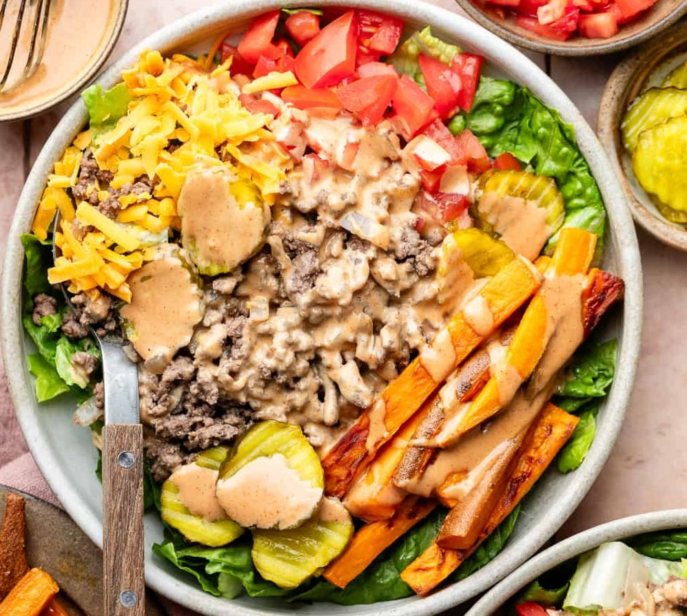 Burger bowl with seasoned steak mince, salad, cheddar, pickles, sweet potato fries and burger sauce